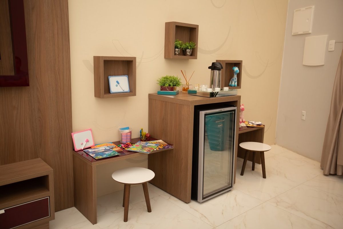 Espaço com café, frigobar e área infantil na sala de espera da Oral Unic Tubarão
