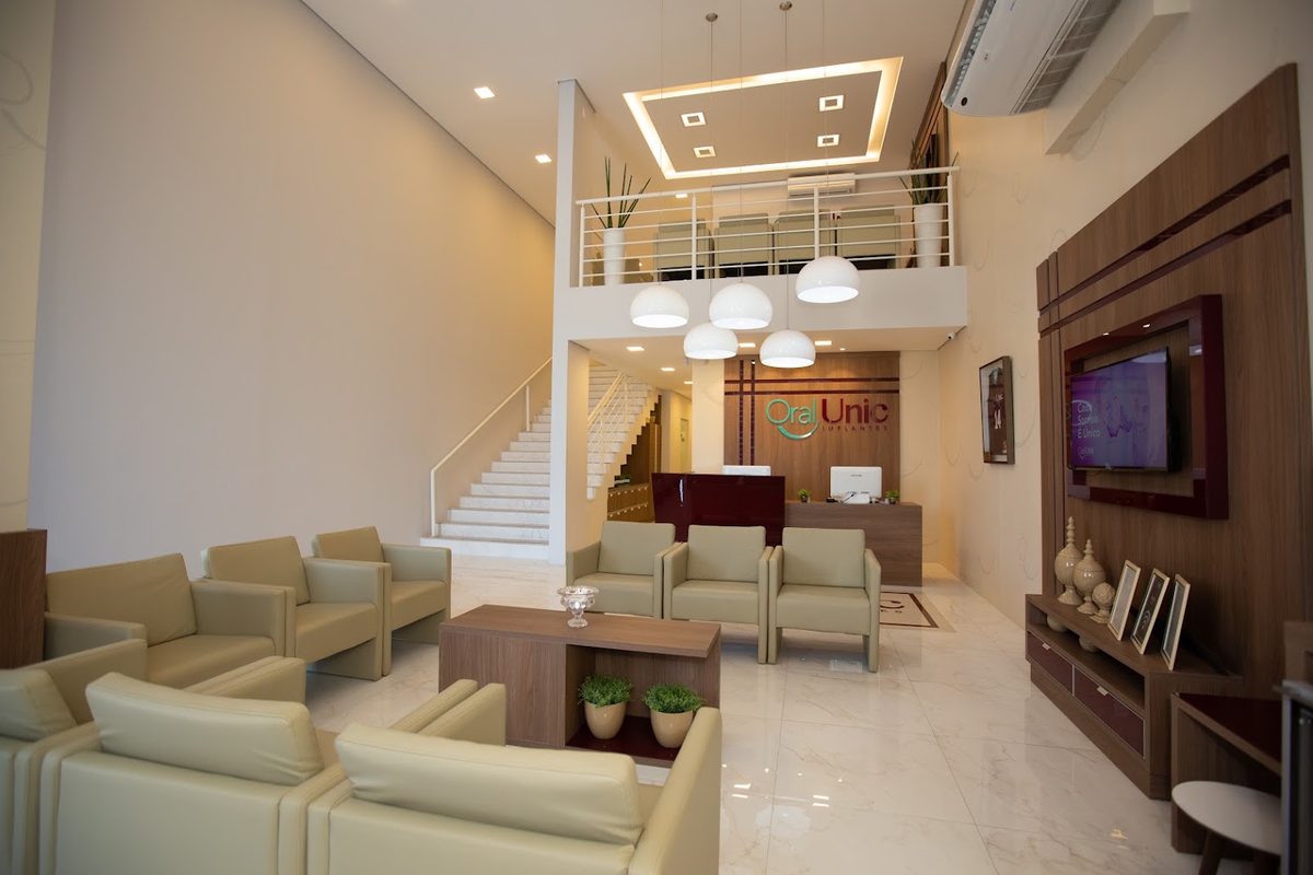 Recepção e sala de espera da Oral Unic Implantes Tubarão, ampla e bem iluminada